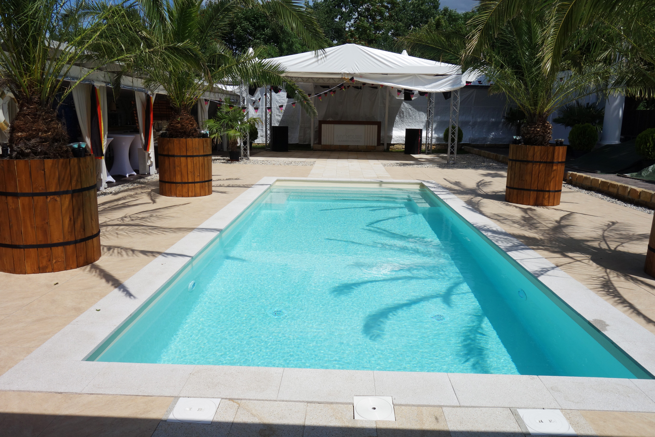 Schwimmbad 4x10x1,35m mit gerader Treppe und Podest, umgeben von Palmen und einem Festzelt