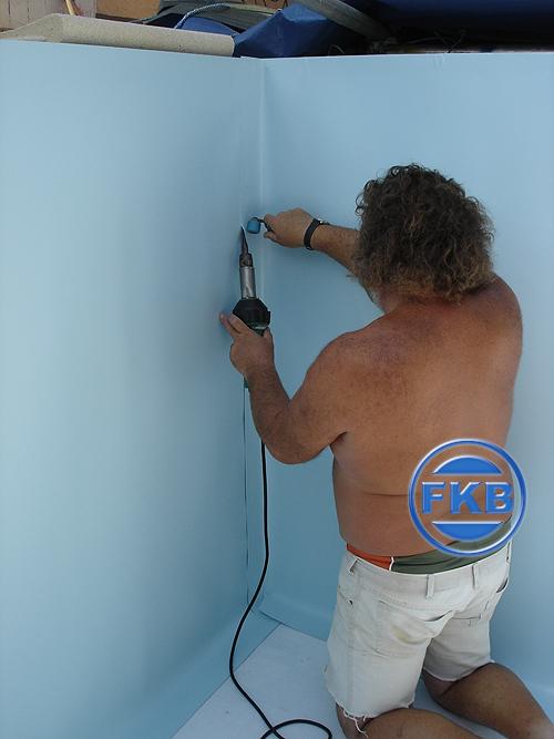 Handwerker schweißt hellblaue Einhängefolie in einer Beckenecke, Detailansicht der Folienverarbeitung