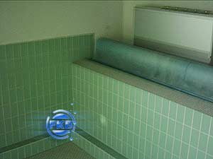 Alte grüne Fliesenwand eines Hallenbades vor der Sanierung, im Hintergrund eine aufgerollte Folie