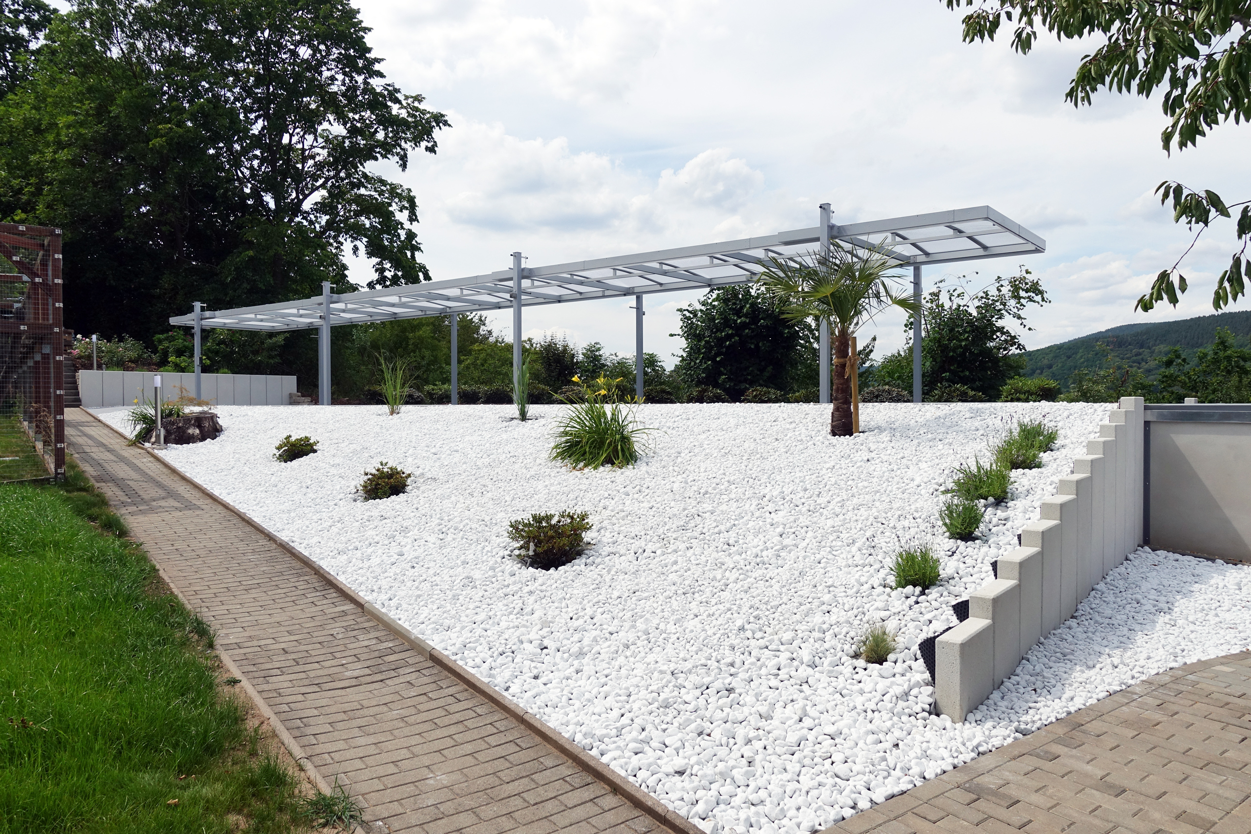 Hubdach-Stahlkonstruktion über dem Langbecken mit weißem Kiesbett im Garten