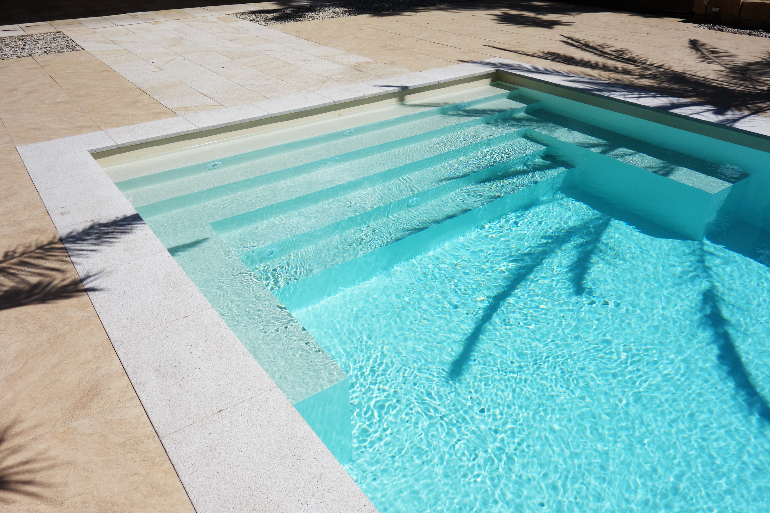 Gerade Treppe und Podest eines Schwimmbads mit hellblauer Einhängefolie und weißem Beckenrand