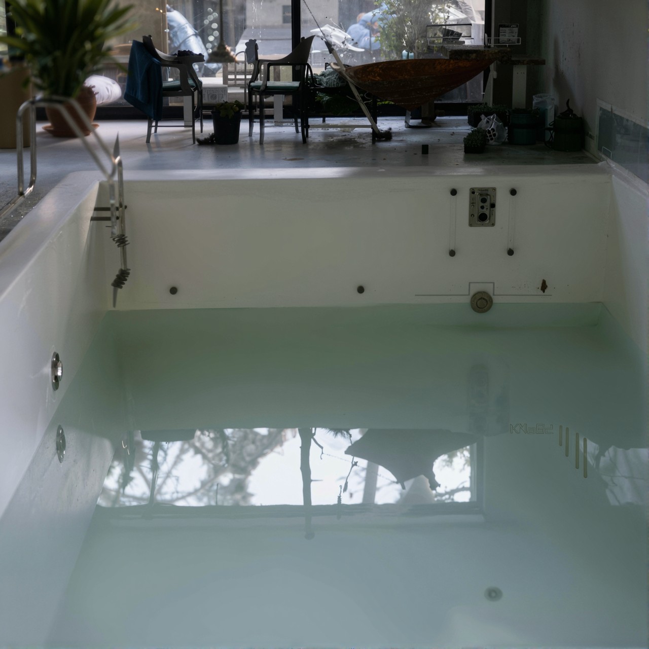 Leerer Pool in einer Schwimmhalle mit Treppe und Technik-Einbauteilen, bereit zur Sanierung.