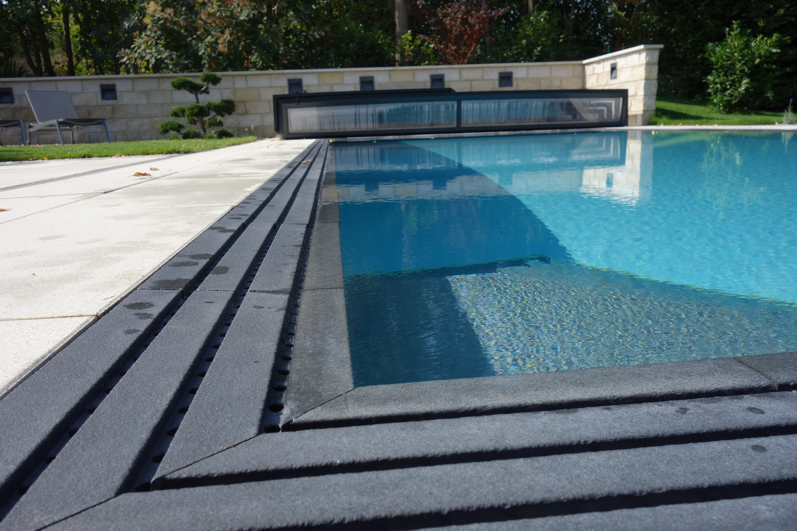 Detailansicht des Überlaufkanals mit Gitterrost und der Wasseroberfläche eines Overflow-Pools.