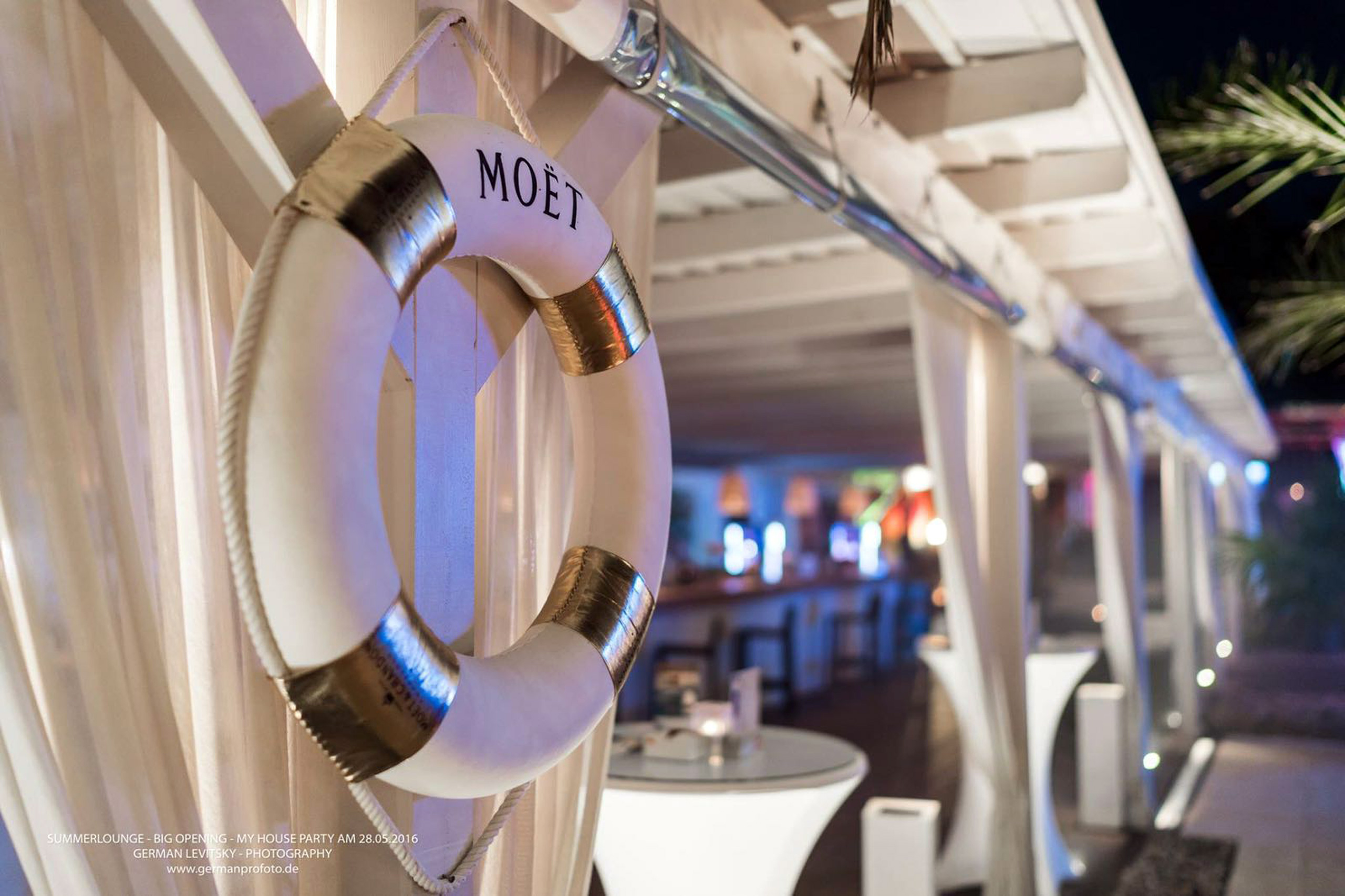 Rettungsring mit "MOËT"-Aufschrift als Dekoration in einer beleuchteten Pool-Lounge