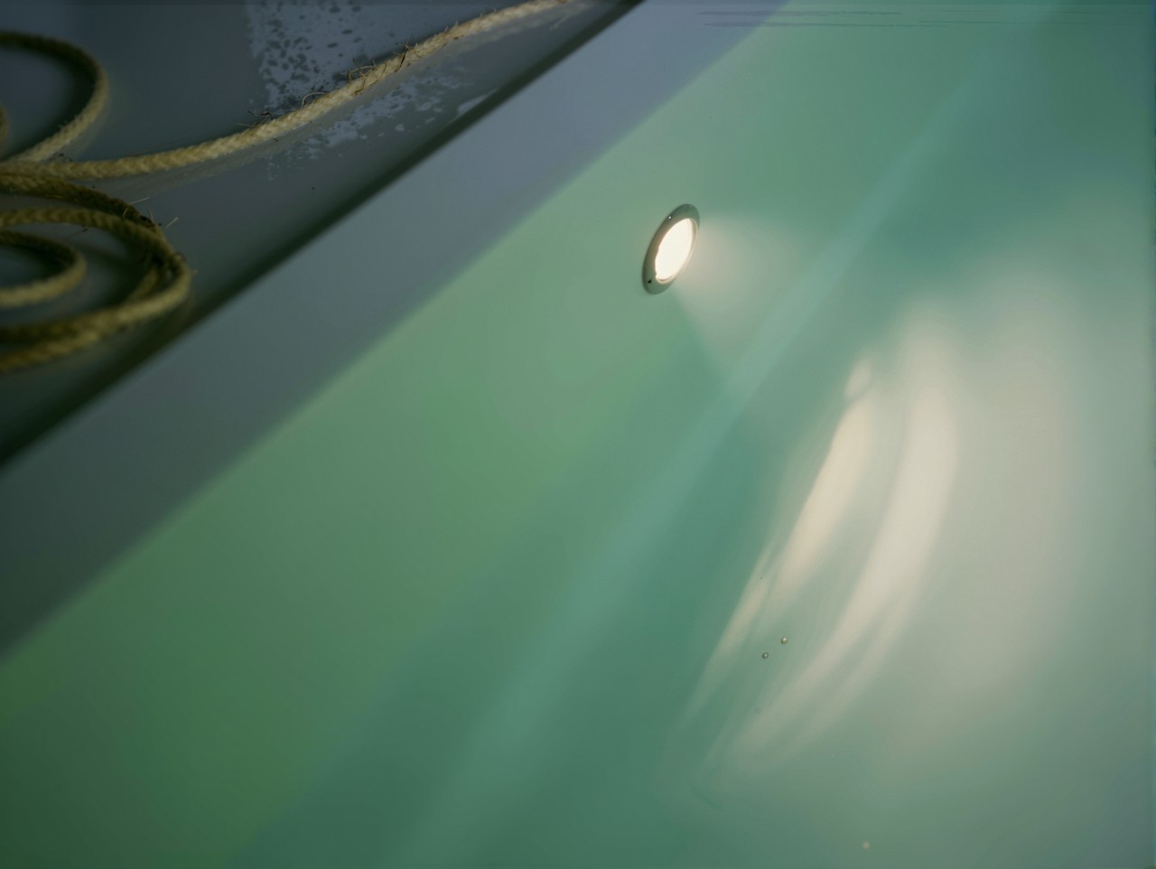 Unterwasser-Scheinwerfer im Hallenbad mit weißer Folie, das Wasser reflektiert das Licht.