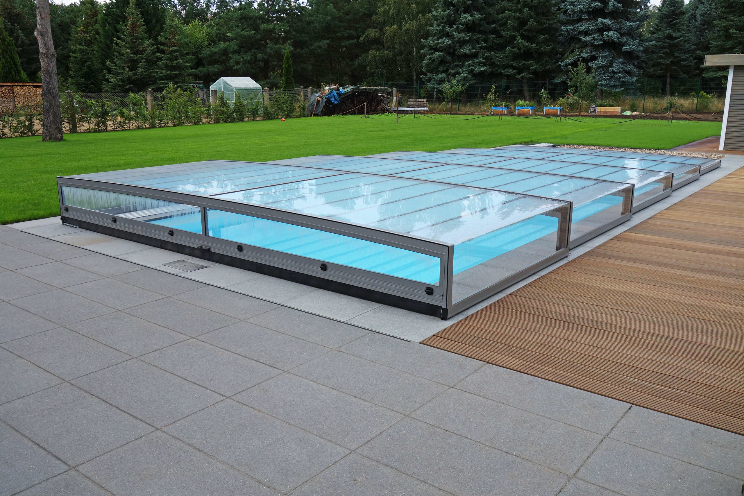 Außenpool mit Überdachung Horizont, umgeben von grauen Fliesen und Holzterrasse