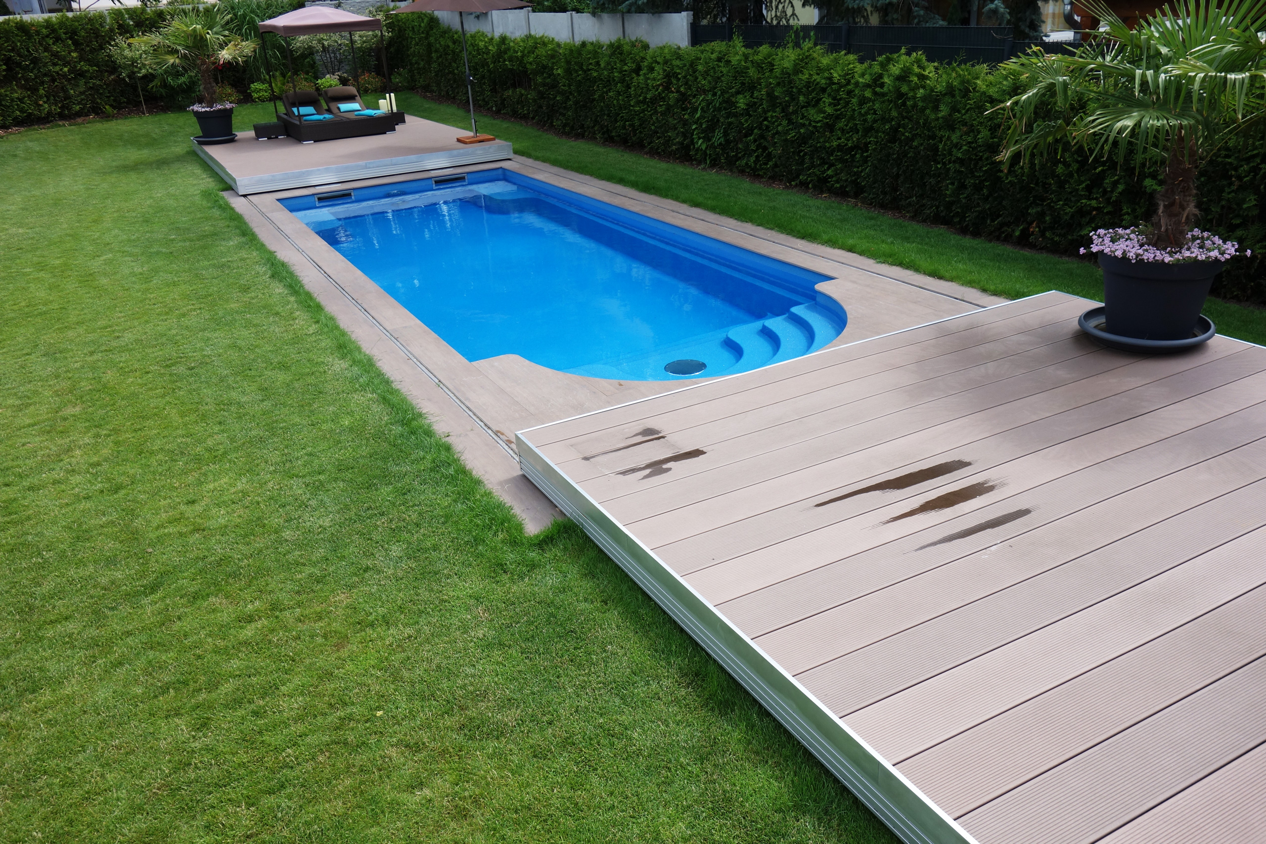 Schwimmbecken Java 101 mit Terrassenabdeckung und Liegefläche im Garten