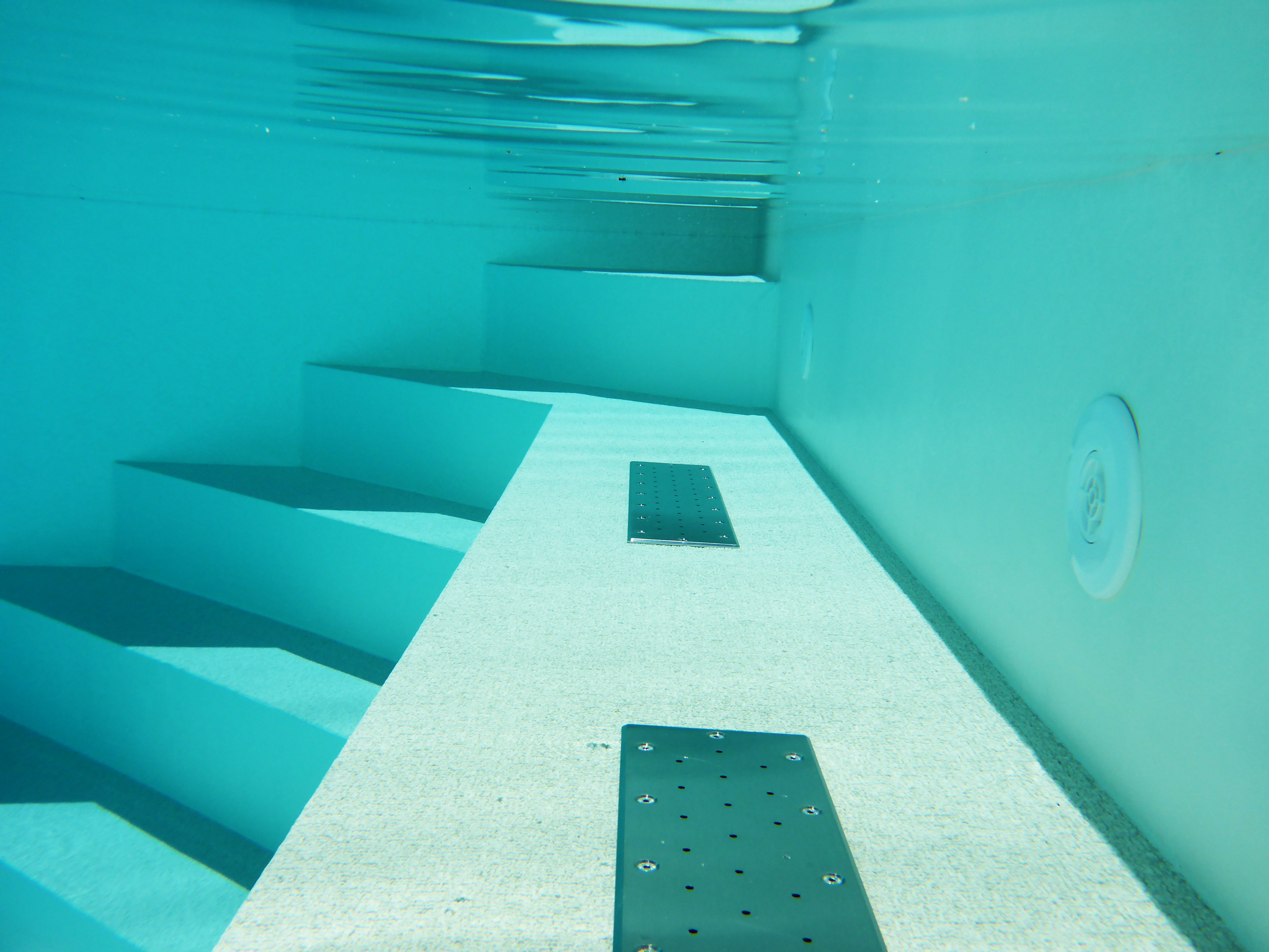 Unterwasseransicht des Pools mit Ecktreppe, Podest und Stehstufe, sowie Einbauteilen an der Wand.