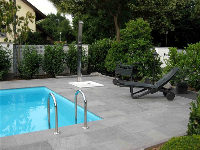 Edelstahl-Poolleiter und Außendusche am türkisblauen Schwimmbecken mit grauen Fliesen