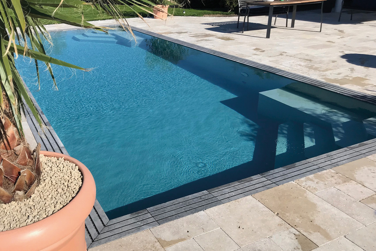 Überlaufbecken Overflow Stone EVO mit 2 Ecktreppen und Sitzbänken, umgeben von einer hellen Steinterrasse