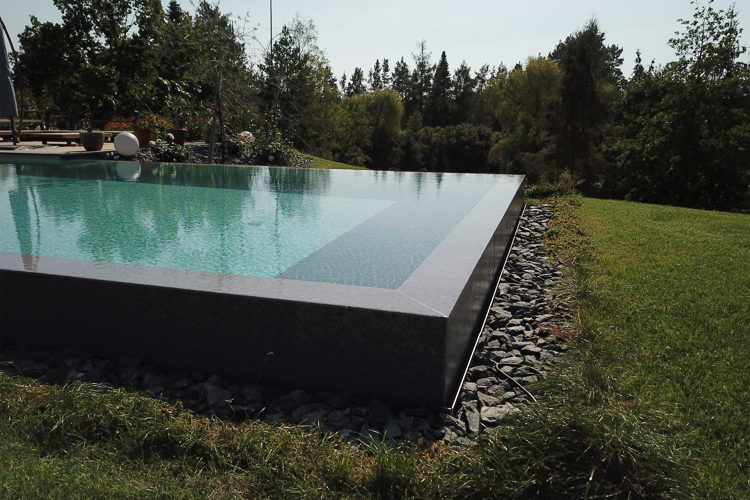 Überlaufbecken mit Überlaufkante und Steinschüttung am Rasenrand