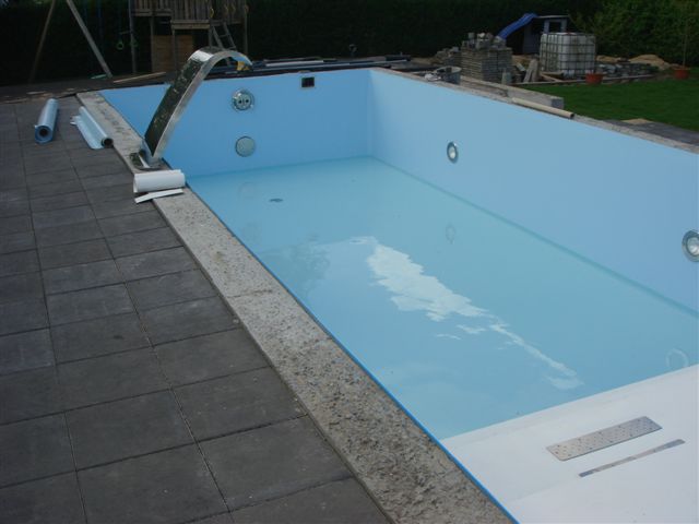 Blaues Becken mit GSA, Schwalldusche und teilweise verlegter Poolfolie am Beckenrand